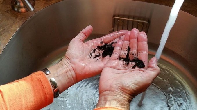 Sie reibt ihre Hände mit gemahlenem Kaffee ein.